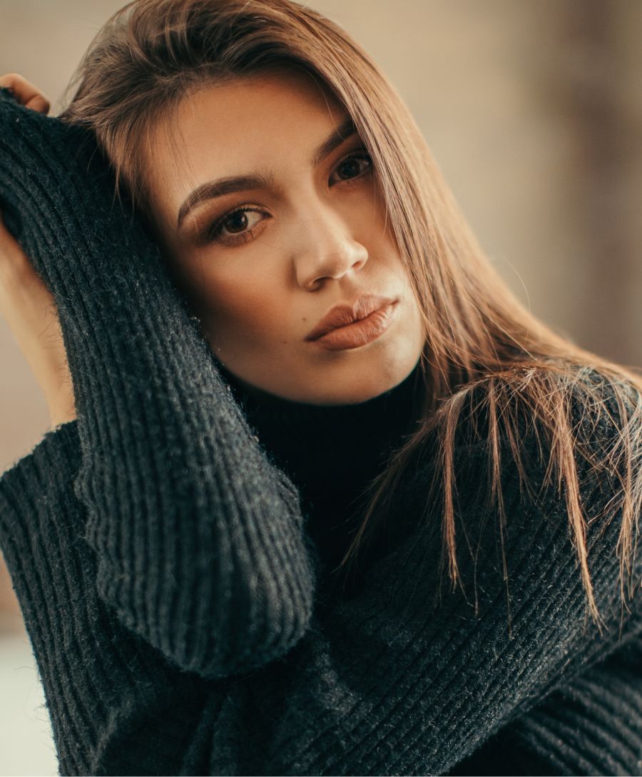 Woman in a black sweater, gazing thoughtfully.