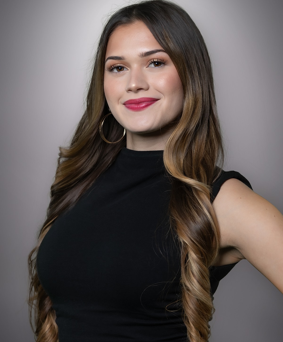 Smiling woman with long hair and hoop earrings.