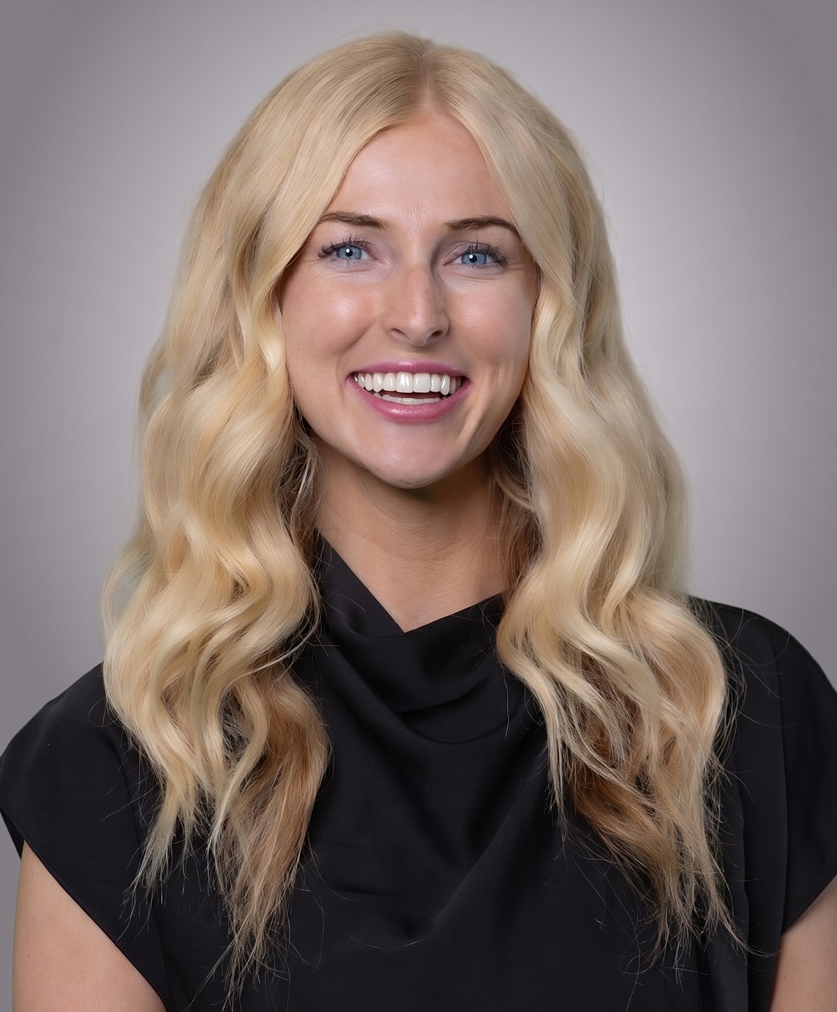 Smiling woman with wavy blonde hair portrait.