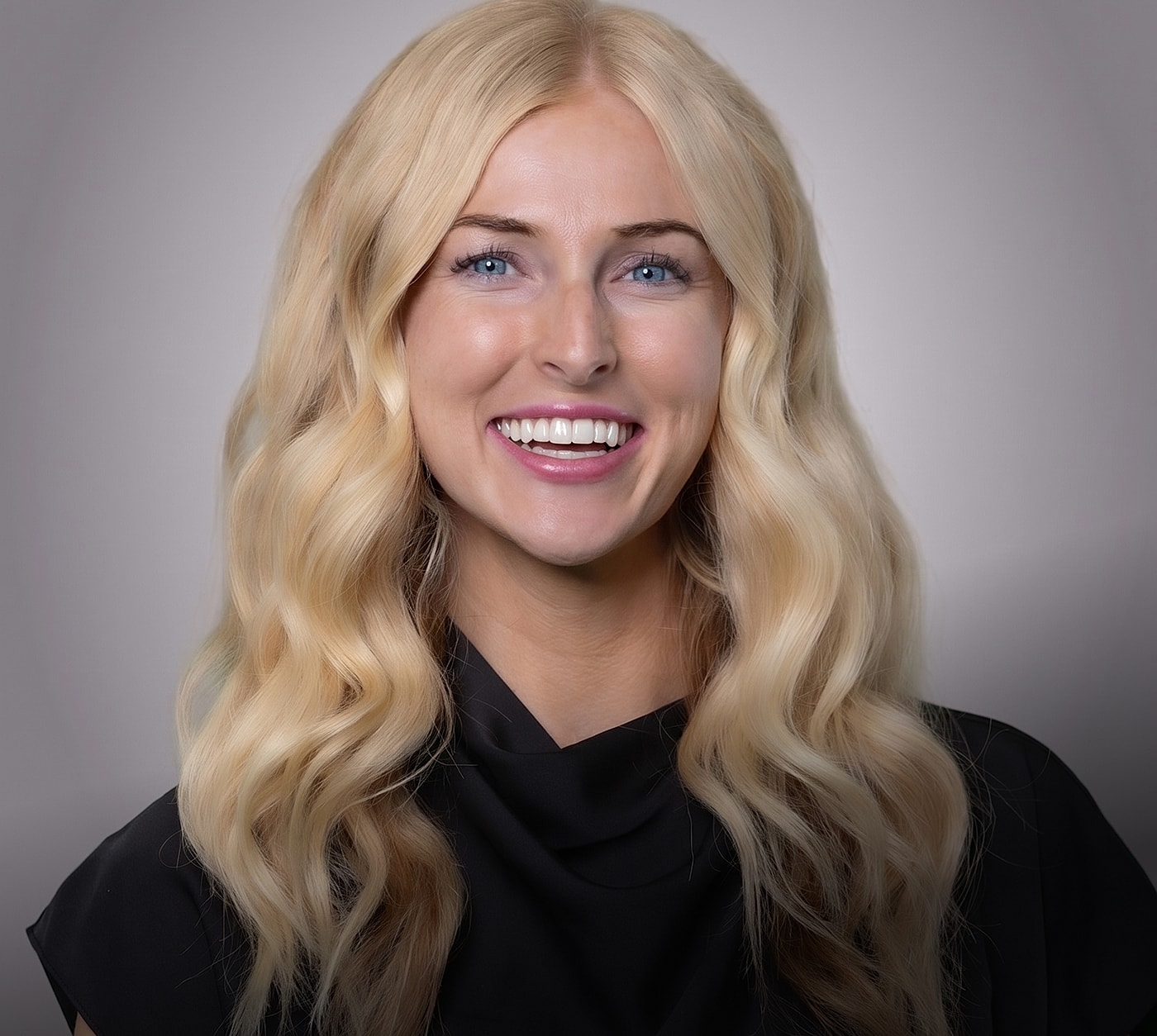 Smiling woman with blonde wavy hair and blue eyes.
