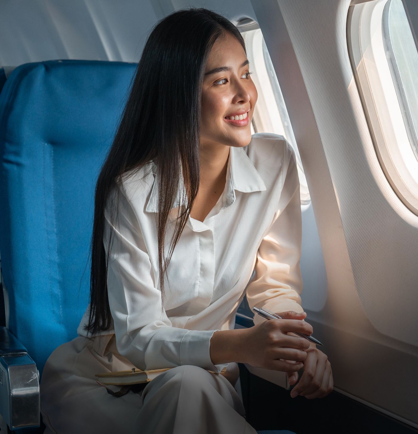 Smiling woman sitting by airplane window.