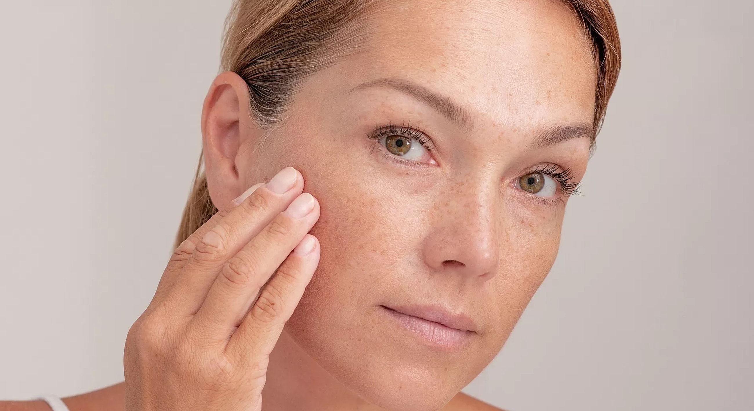 Woman applying skincare to her face.