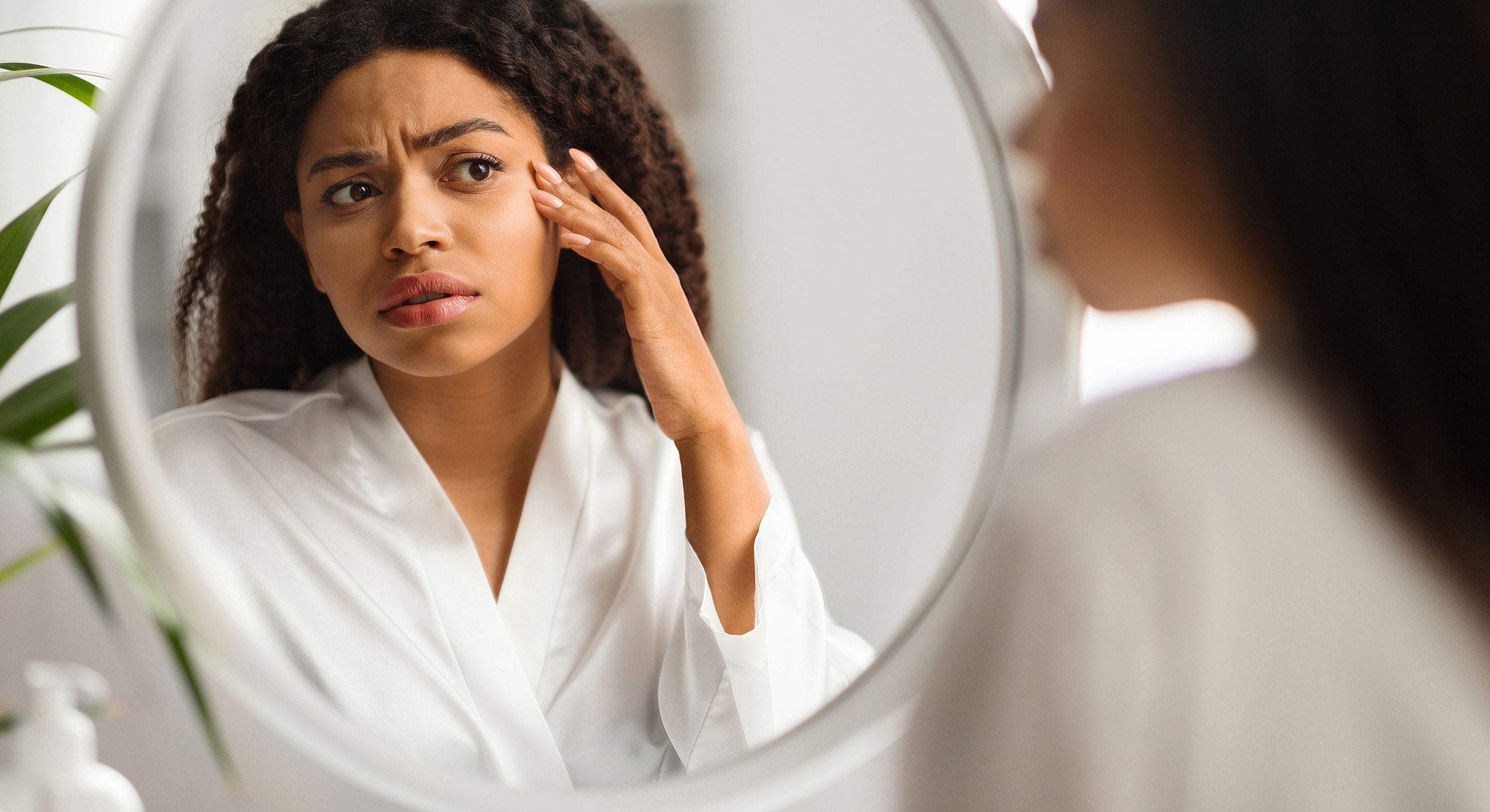 Woman examining her skin in a mirror.