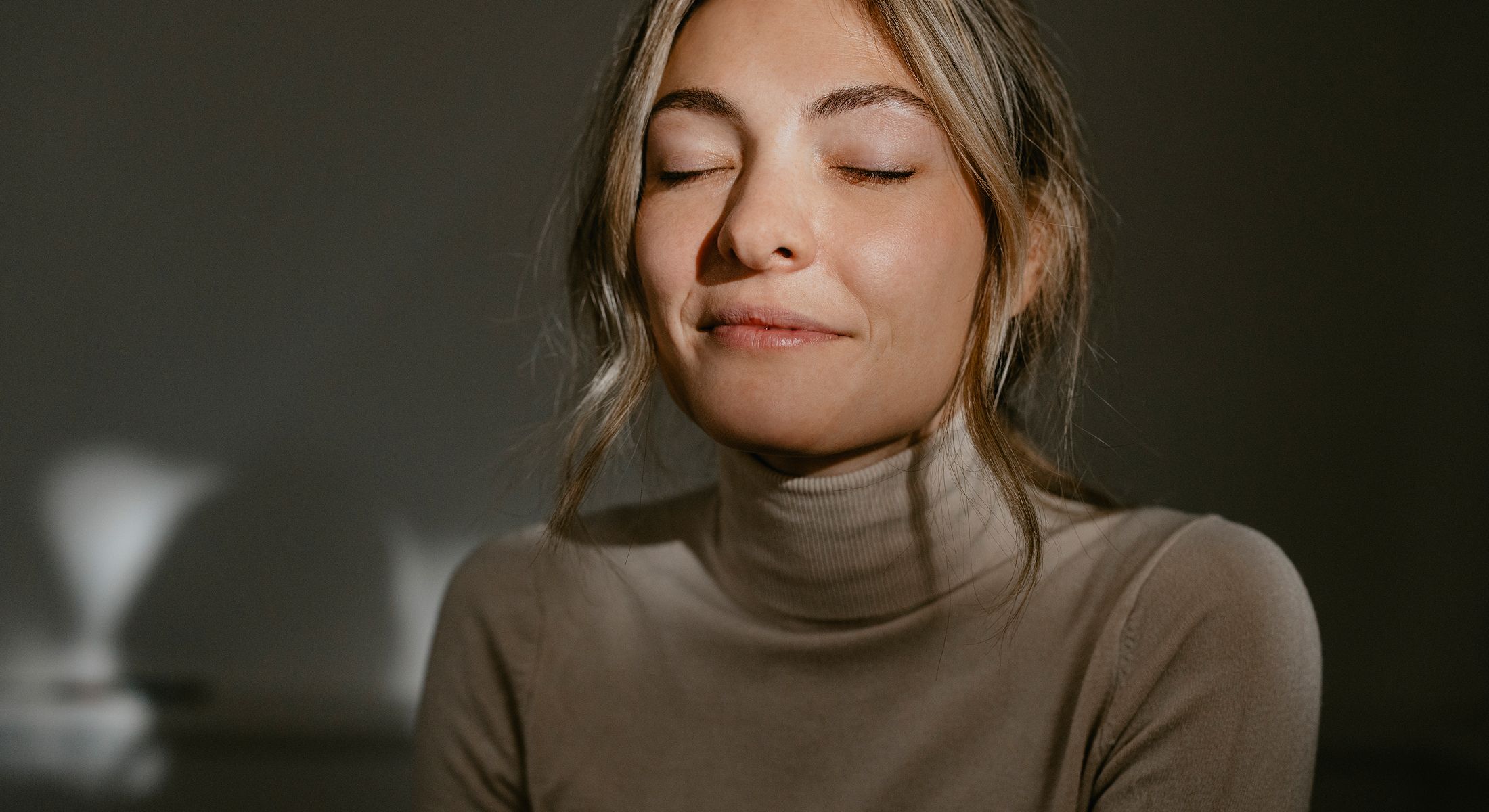 Woman with closed eyes in soft lighting.