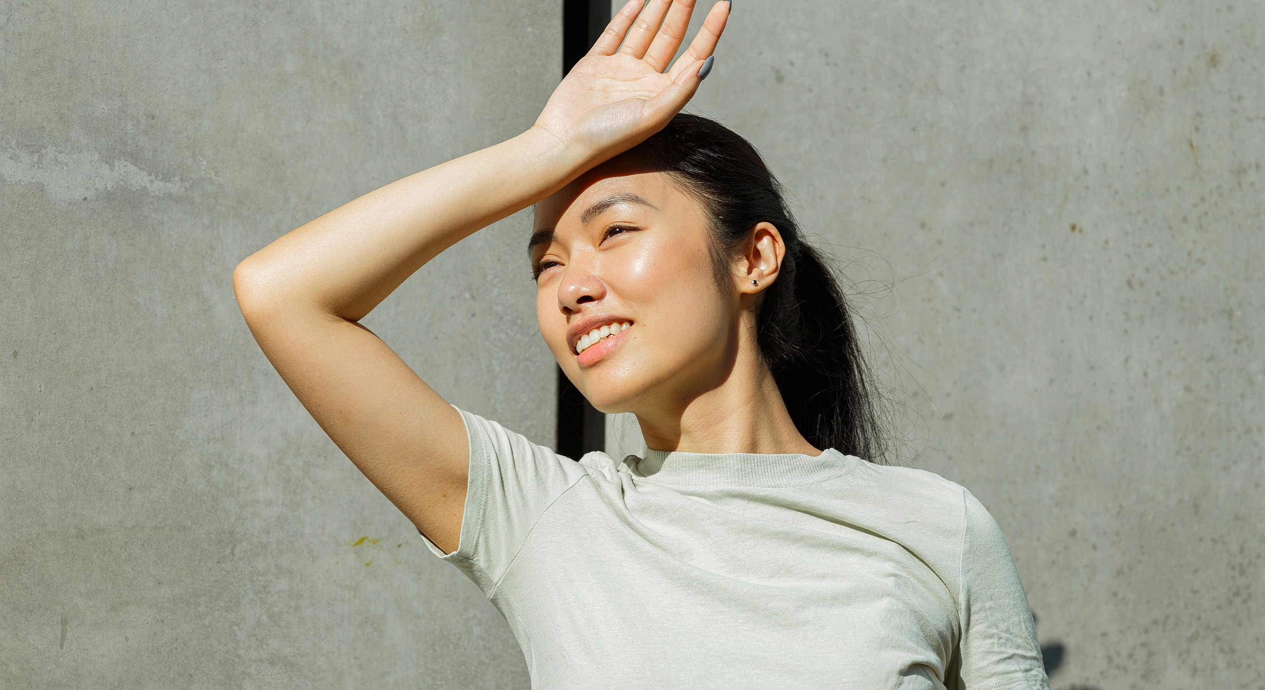 Woman enjoying sunlight against a concrete background.