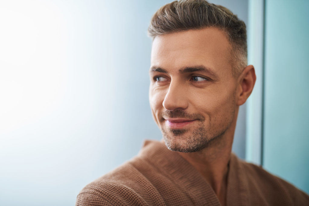 Handsome young man expressing positive emotions on blue background